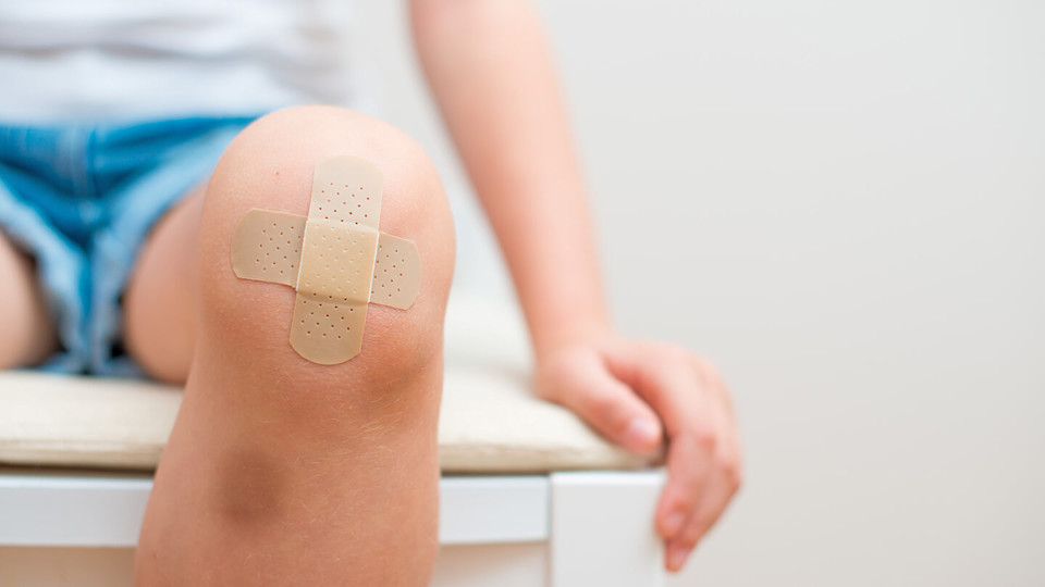 Child with plaster on injured grazed knee