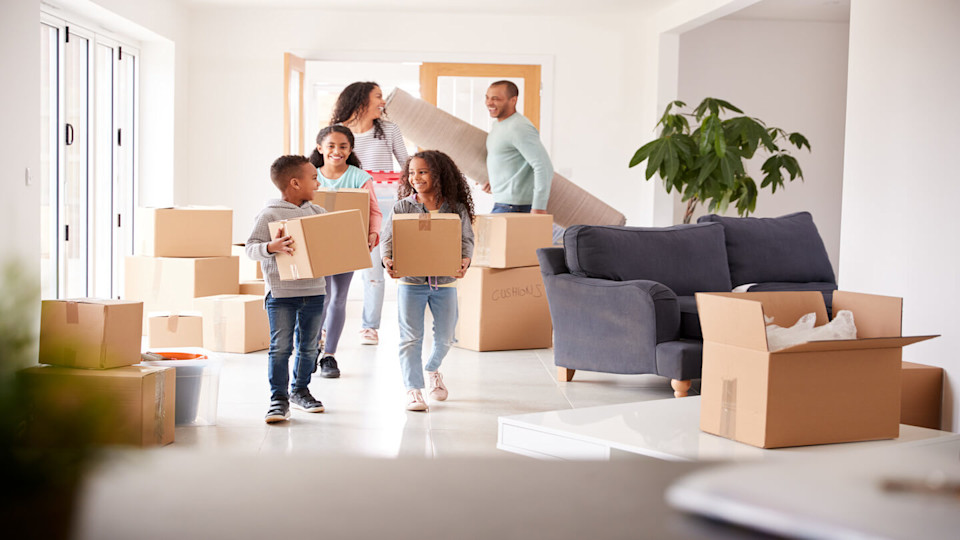 Family with 3 children carrying boxes in a house