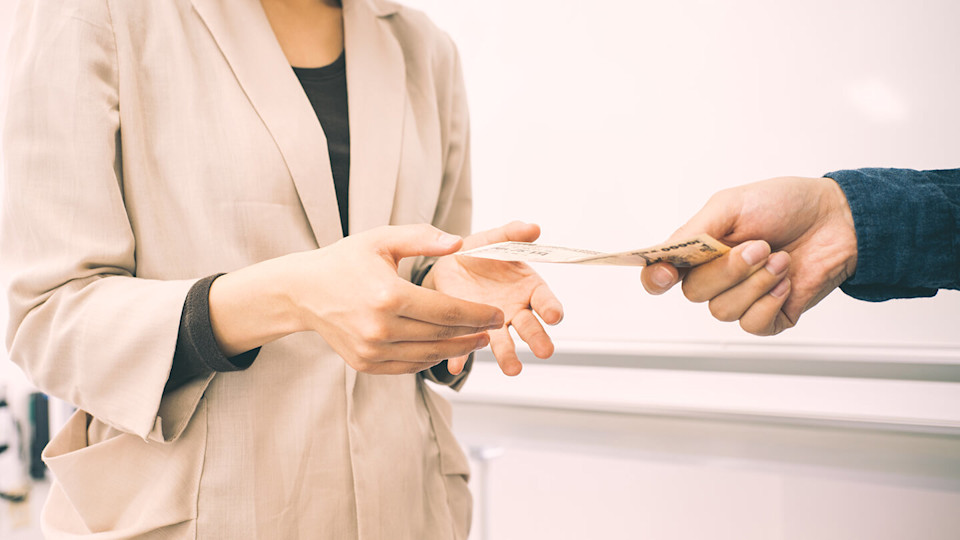 Man handing over cash bank note to woman