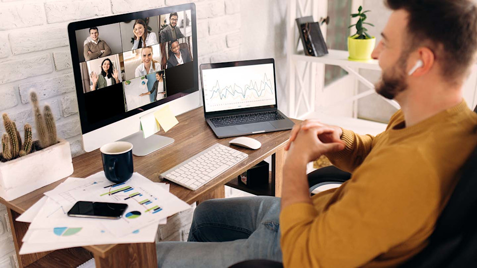 Man at work desk on video call with colleagues