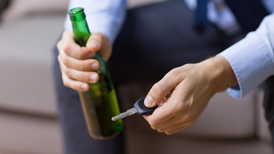 Holding car keys and drinking a beer