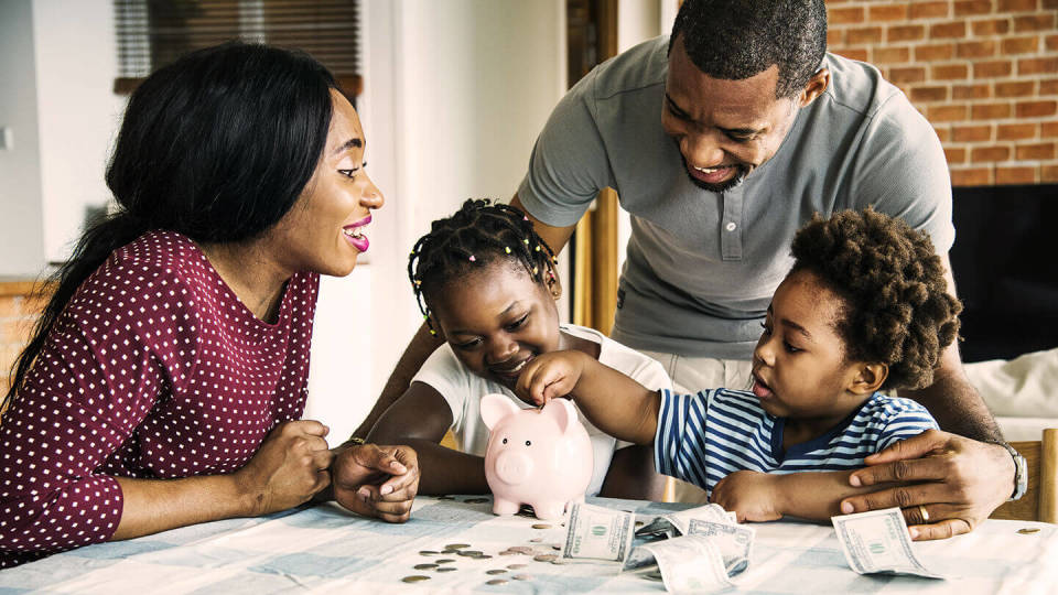 Young family sat around a piggy bank with two children
