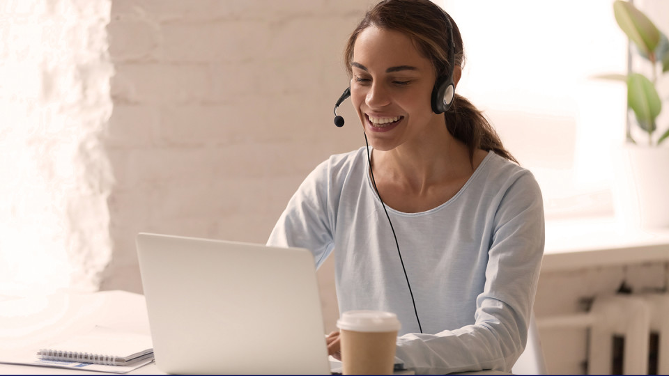 Woman at laptop smiling with headphones on