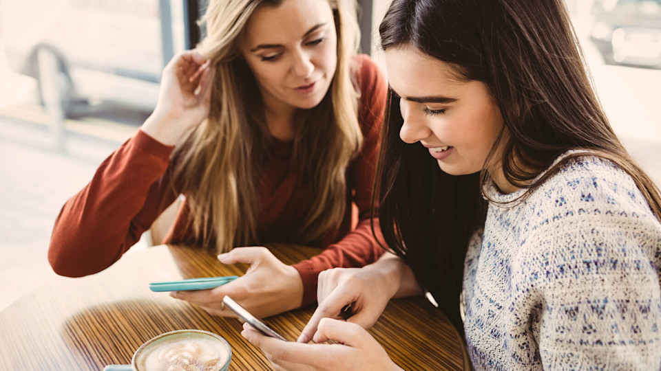 Friends using smartphone and having a coffee