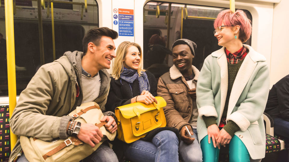 Group of teenagers on a train smiling and laughing