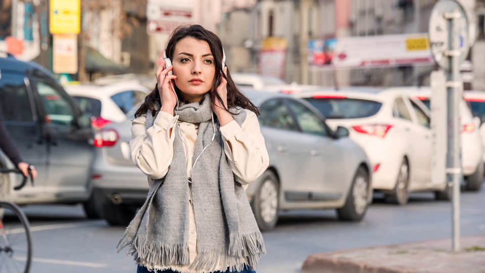Woman in headphones in traffic - cars