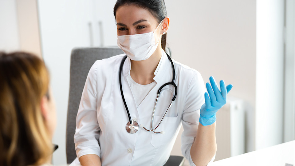 Doctor wearing mask talking to patient