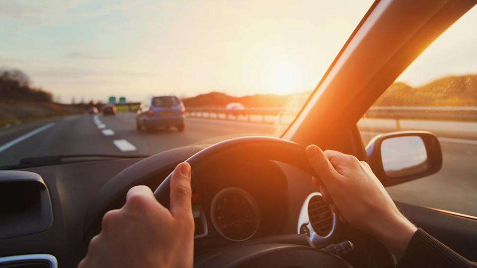 Hands on the wheel of a car driving along the motorway