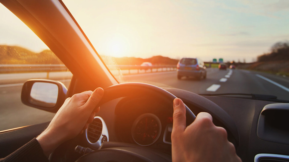 Hands on the wheel of a car driving along the motorway