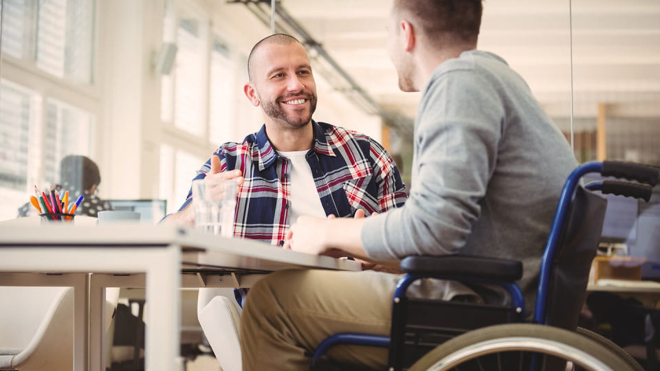Friendly man chatting to another man in wheelchair