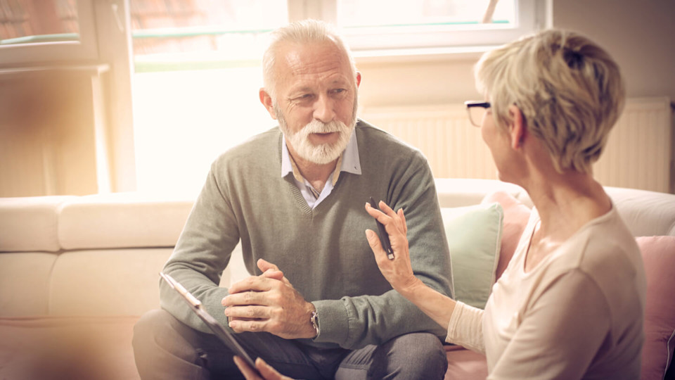 Elderly man and woman talking on a couch