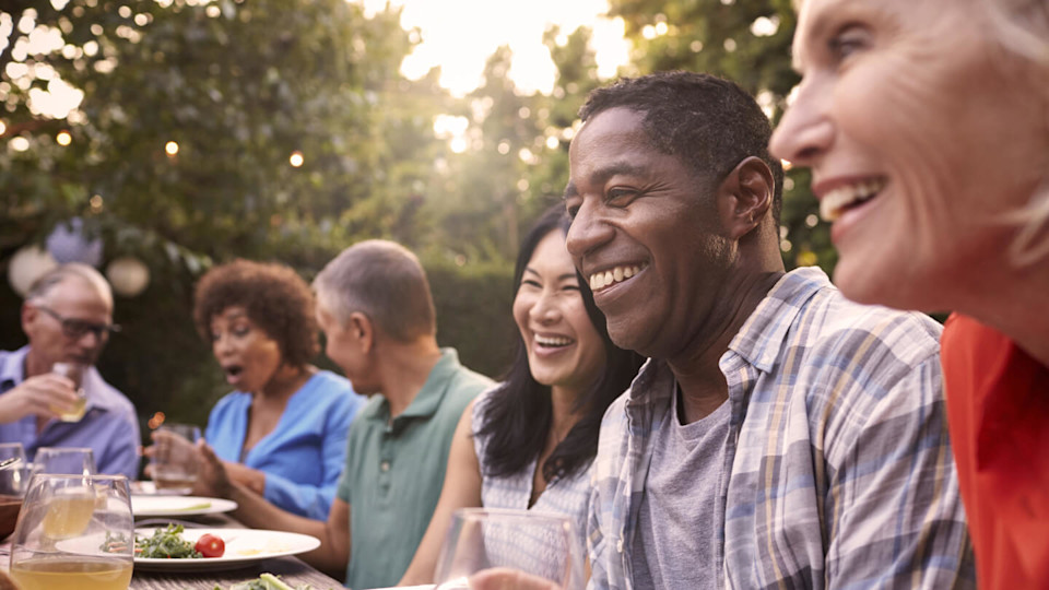 Large group of individuals eating happily outdoors