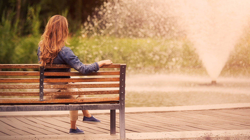 Woman on bench in front of water feature