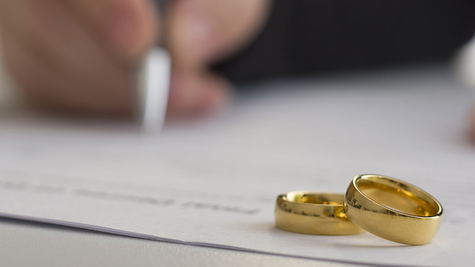 Hands of wife, husband signing decree of divorce, dissolution, canceling marriage, legal separation documents, filing divorce papers or premarital agreement prepared by lawyer. Wedding ring.