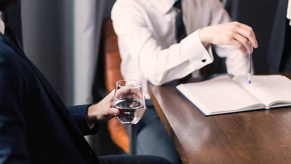 Newsroom imagery - man drinking water in business meeting