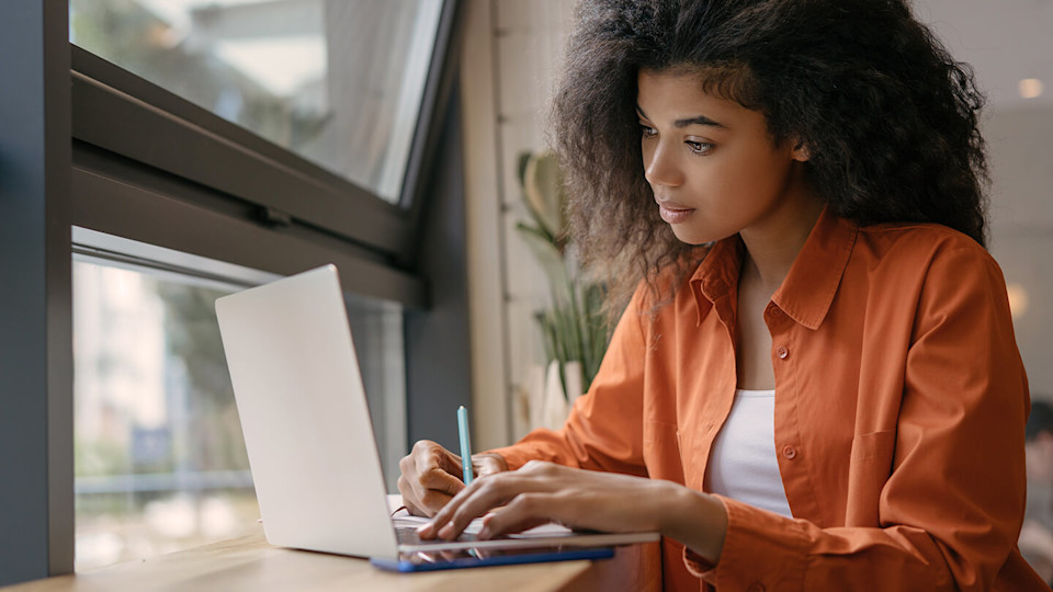 Female student using laptop and taking notes