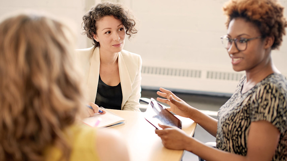 Smartly dressed woman listening to friend with Ipad