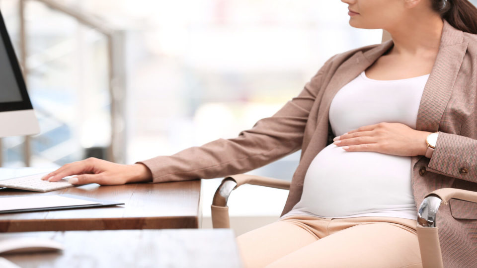 Newsroom - Pregnant woman sat at an office desk