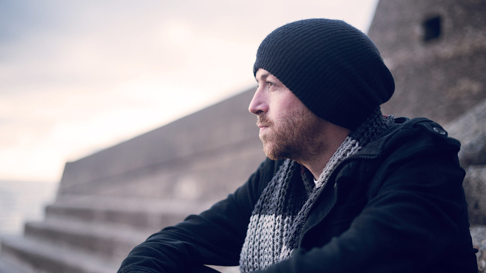 Young man sitting outside on chilly day