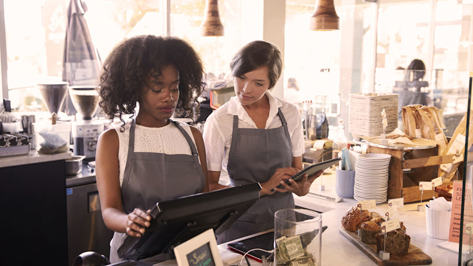 New starter being taught how to use checkout till