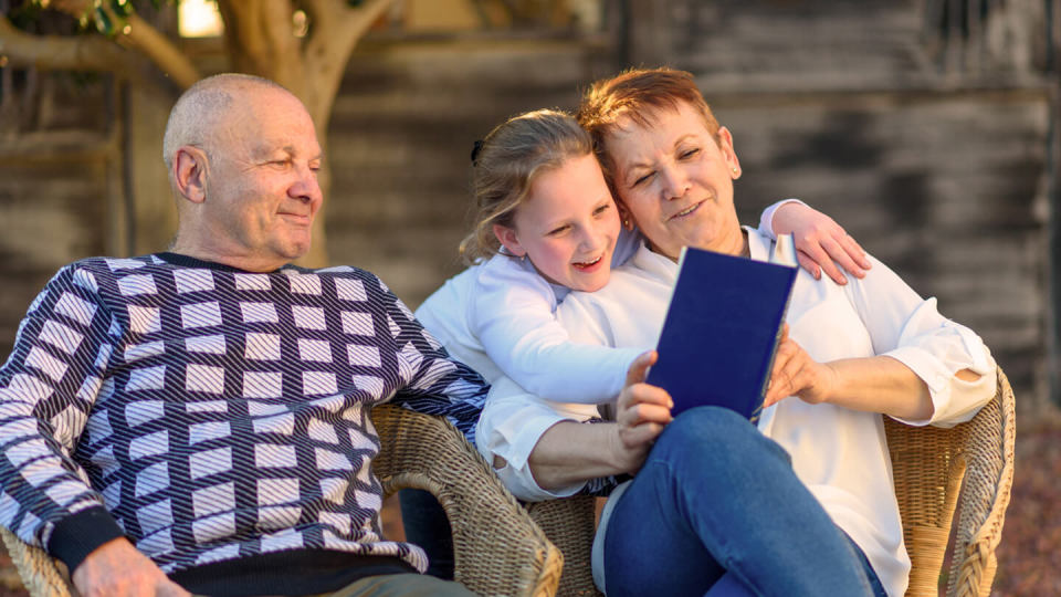 Family happily sitting outside, reading book