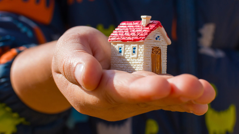 Hand holding small model house