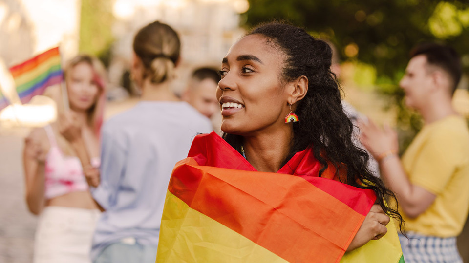 LGBTQ+ woman wrapped in flag on Pride march
